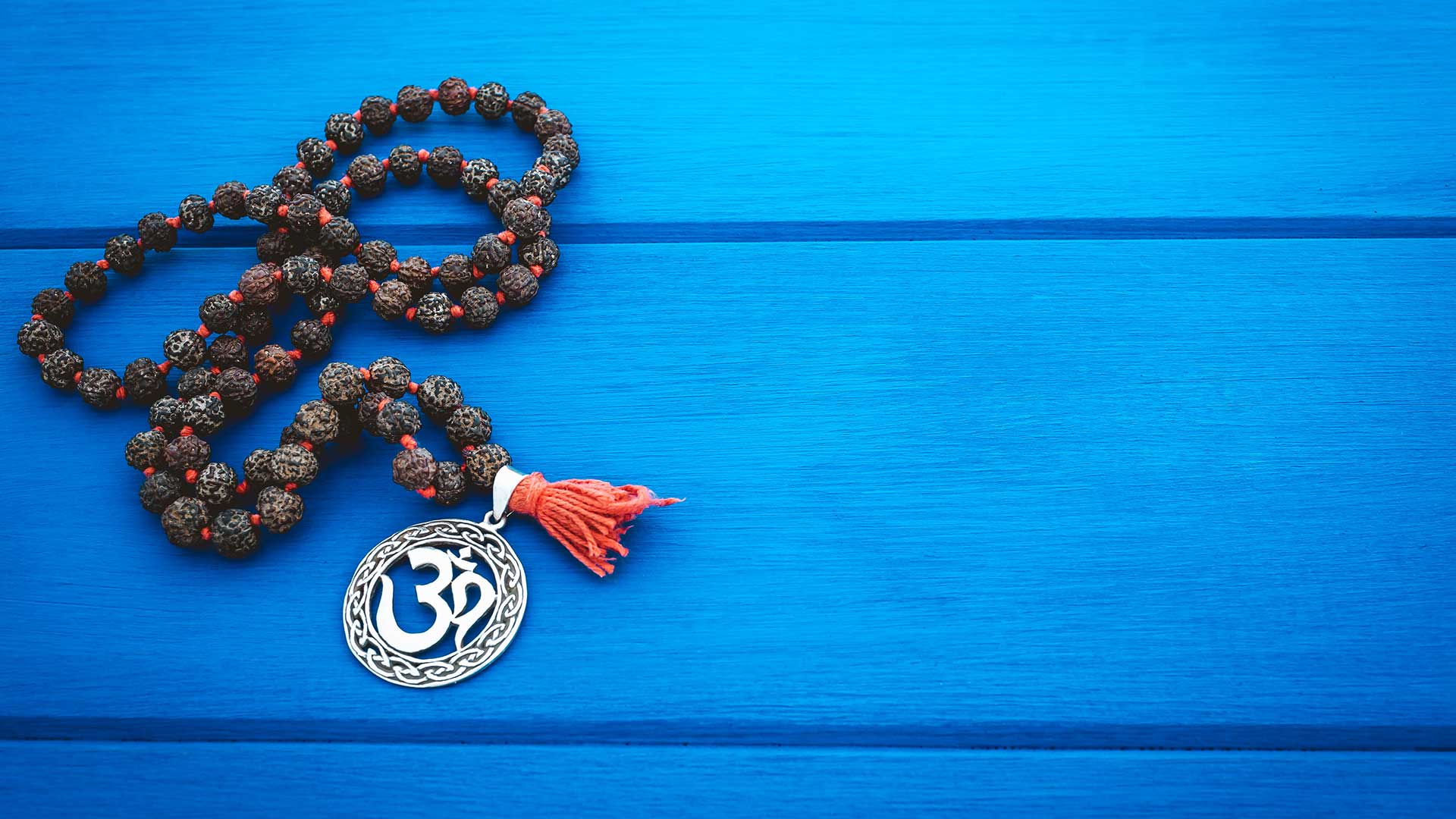 Un mâlâ de rudraksha et son pendentif om, sur un bois bleu